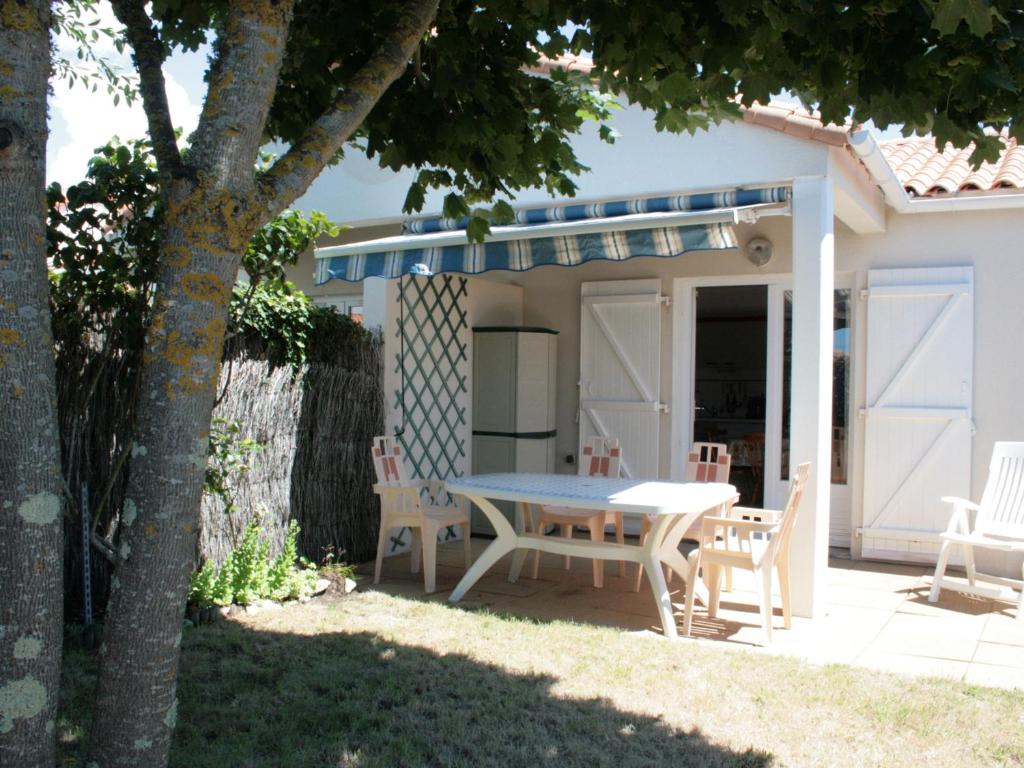 un patio avec une table et des chaises devant une maison dans l'établissement Maison proche plage et commerces, 2 chambres, jardin, parking privé - FR-1-22-209, à La Tranche-sur-Mer