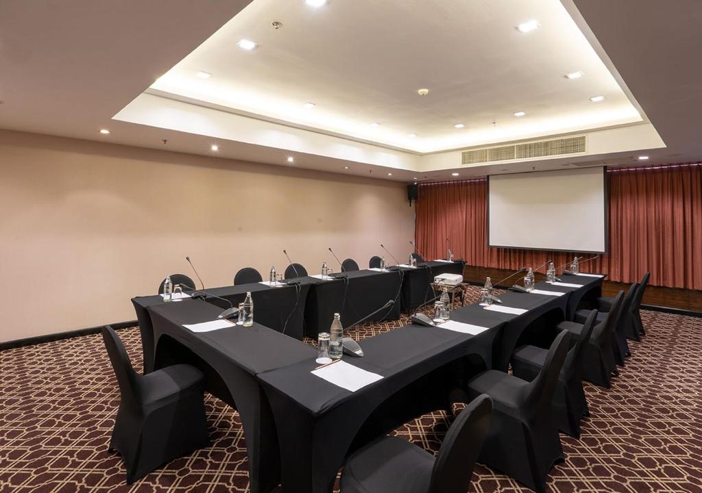 A formal conference room arranged around long tables with a projection screen.