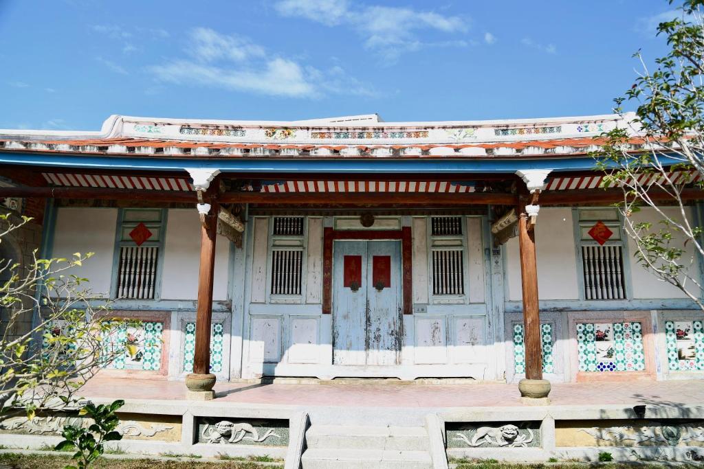 ein weißes Gebäude mit einer roten Tür davor in der Unterkunft 怪獸村屋民宿 in Gukeng