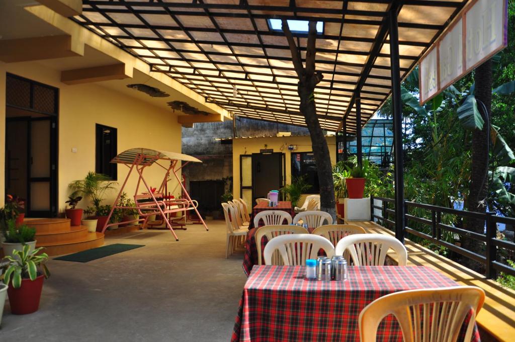 un patio al aire libre con mesas, sillas y toldo en Hotel Oasis, en Mount Abu