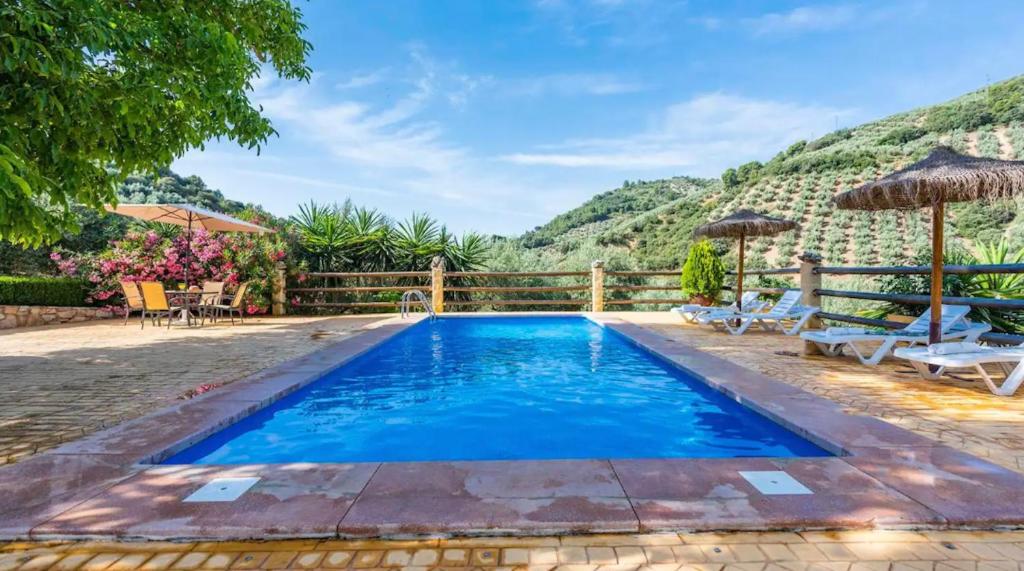una piscina con sillas y sombrillas junto a una montaña en 6 bedrooms villa with private pool furnished garden and wifi at Montefrio, en Montefrío