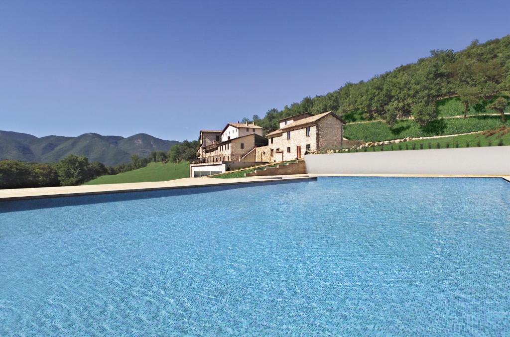 a swimming pool with blue water in front of a house at Relais Villa D'Assio in Labro