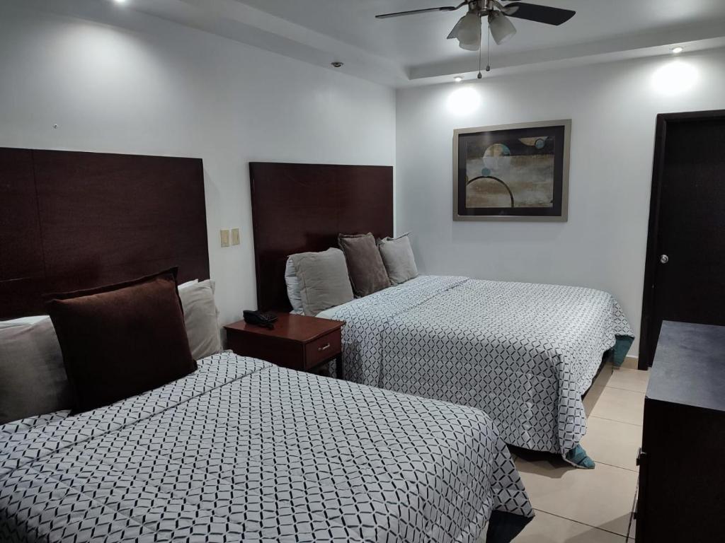 a hotel room with two beds and a ceiling fan at Hotel Don Quijote in Mexicali
