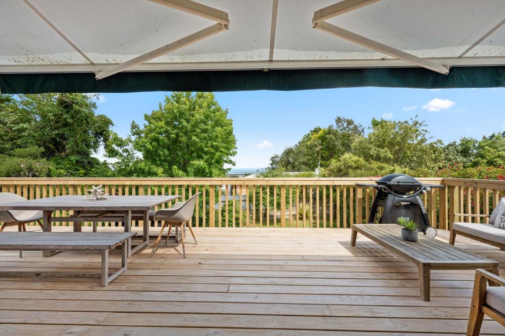 een terras met tafels en stoelen en een grill bij Waitahanui Lake House - Lake Taupo Holiday Home in Waitahanui