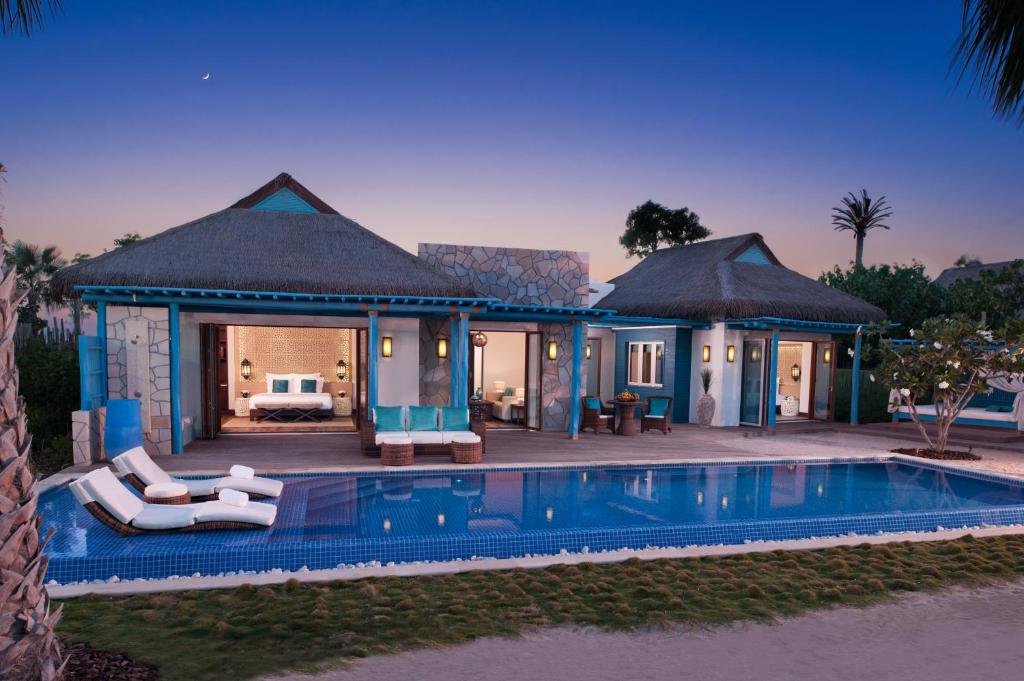 a villa with a swimming pool next to a resort at Banana Island Resort Doha by Anantara in Doha