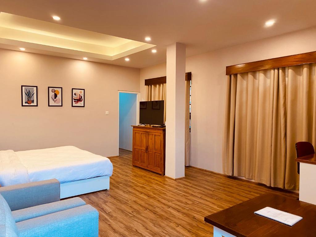 a hotel room with a bed and a flat screen tv at THE APARTMENT in Gangtok
