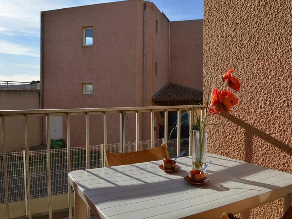 une table avec un vase de fleurs sur un balcon dans l'établissement Appartement T2 à Saint Pierre la Mer, proche plage, loggia sud, parking, animaux acceptés - FR-1-229D-272, à Saint Pierre La Mer