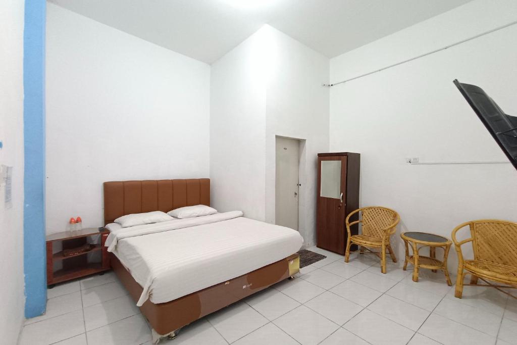 1 dormitorio con 1 cama, mesa y sillas en OYO 92207 Hotel Koperasi en Banda Aceh