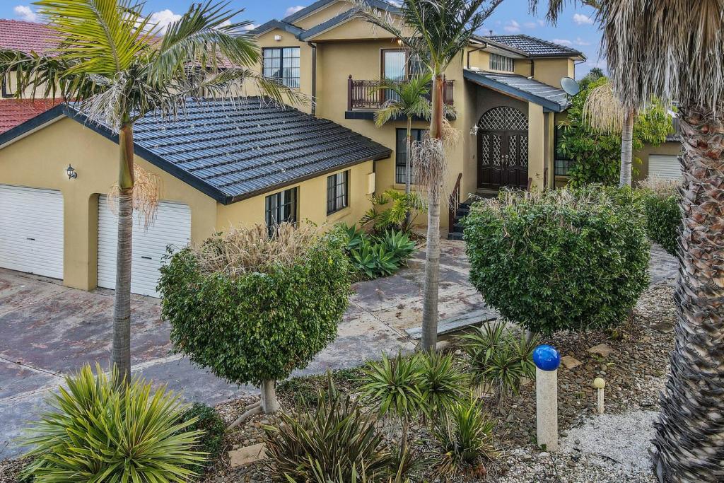 a yellow house with palm trees in front of it at 12 mins to Mel Airport-Good Wood House in St Albans