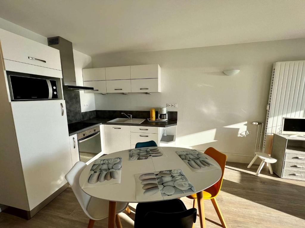 une cuisine avec une table et des chaises et un réfrigérateur blanc dans l'établissement Studio rénové à Quiberon, parking et vue mer - FR-1-478-137, à Quiberon