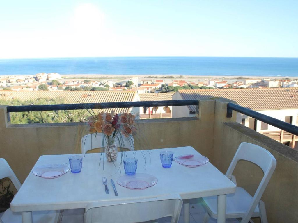 une table blanche et des chaises sur un balcon avec l'océan dans l'établissement Appartement T2 - Mezzanine 5 couchages avec piscine et parking - FR-1-229D-58, à Fleury