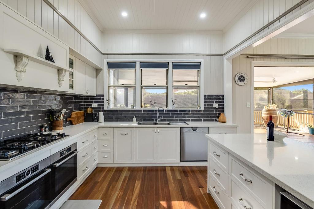 a kitchen with white cabinets and a stove top oven at Elegant, Stunning & Central! East Side Gem! in Toowoomba