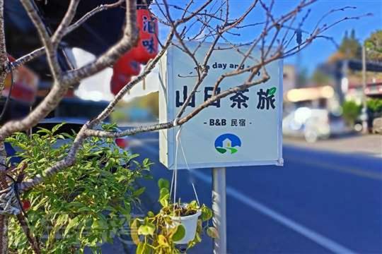 un signe devant un arbre avec une plante dans l'établissement 阿里山-山日茶旅民宿, à Le-yeh
