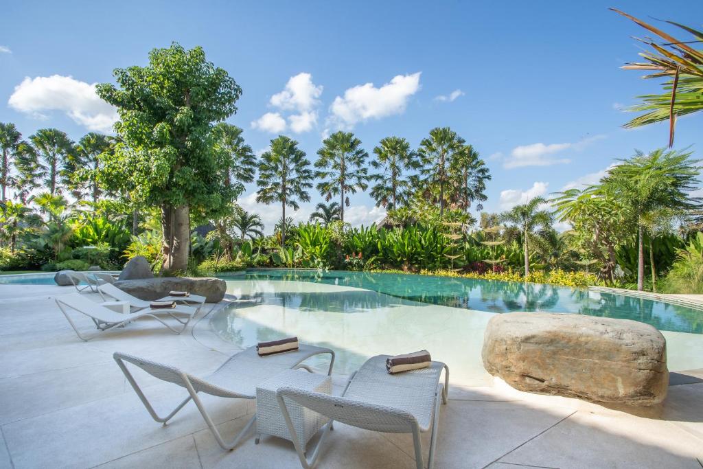 a resort pool with chairs and a large rock at Sanctoo Suites & Villas in Sukawati