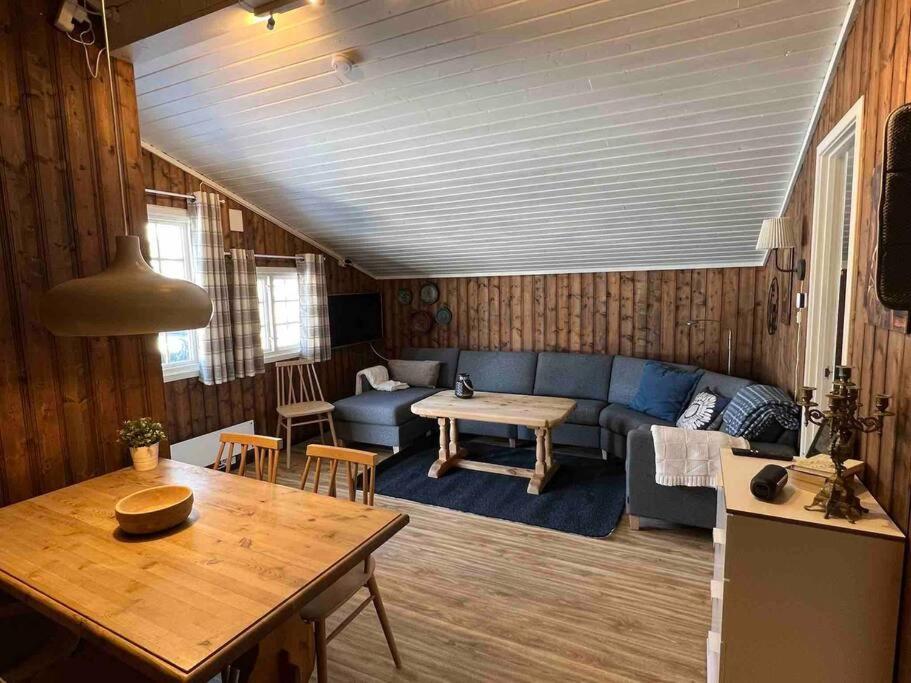 ein Wohnzimmer mit einem blauen Sofa und einem Tisch in der Unterkunft Koselig hytte med uteplas ved Hallingdalselva in Ål