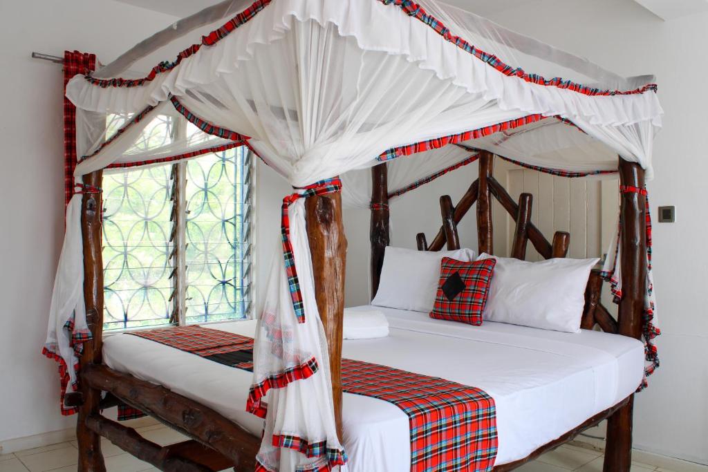 two beds in a bedroom with a canopy bed at The Beach House by Maasai in Mombasa