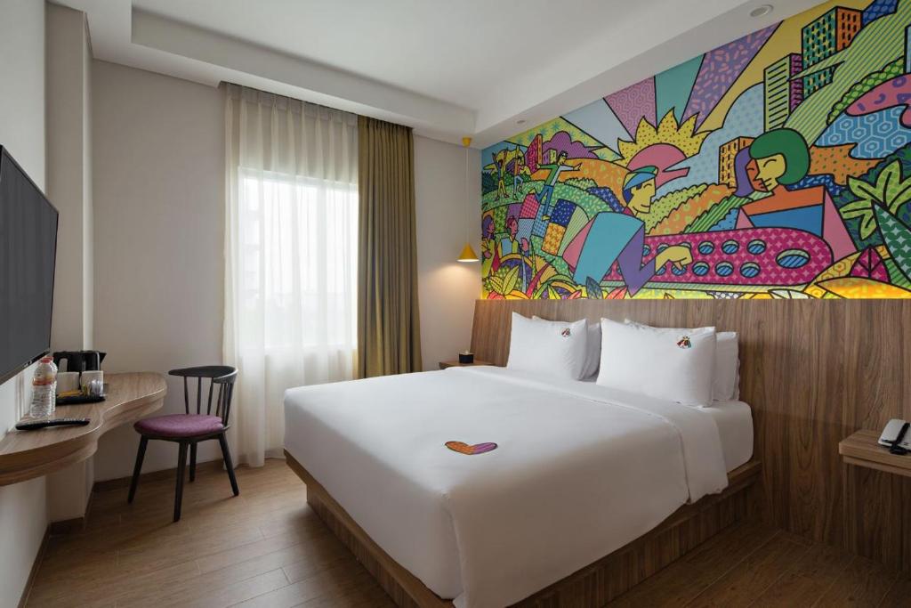 una habitación de hotel con una cama grande y una pintura en la pared en MaxOneHotels at Kota Harapan Indah-Bekasi en Bekasi