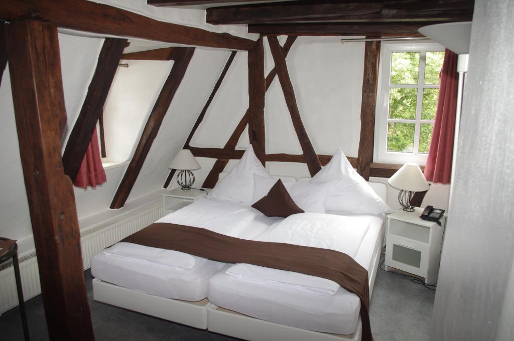 Schlafzimmer mit einem weißen Bett und Holzbalken in der Unterkunft Altes Badhaus in Eberbach
