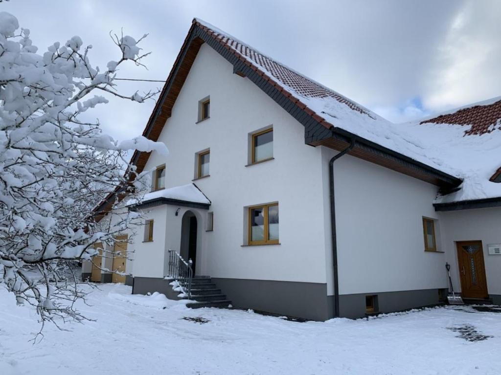 una casa blanca con nieve en el techo en Ferienwohnung Eifelhöhe Pützer, en Hellenthal
