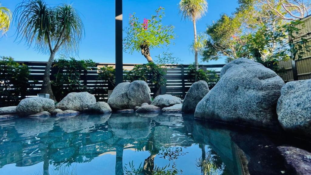 a pool of water with rocks and palm trees at Route Inn Grantia Aoshima Taiyokaku in Miyazaki