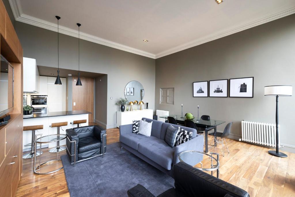 a living room with a couch and a kitchen at JOIVY Chic 2BR Apt with City Views at the Heart of Old Town in Edinburgh
