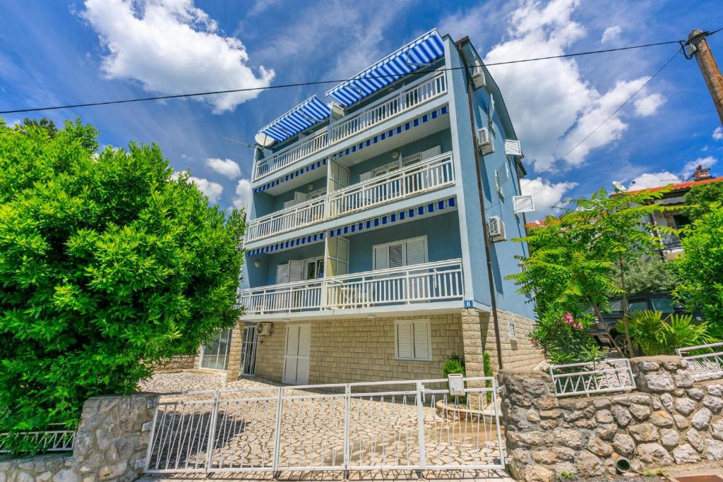 a blue building with white balconies and trees at PODVEZANEC in Dramalj