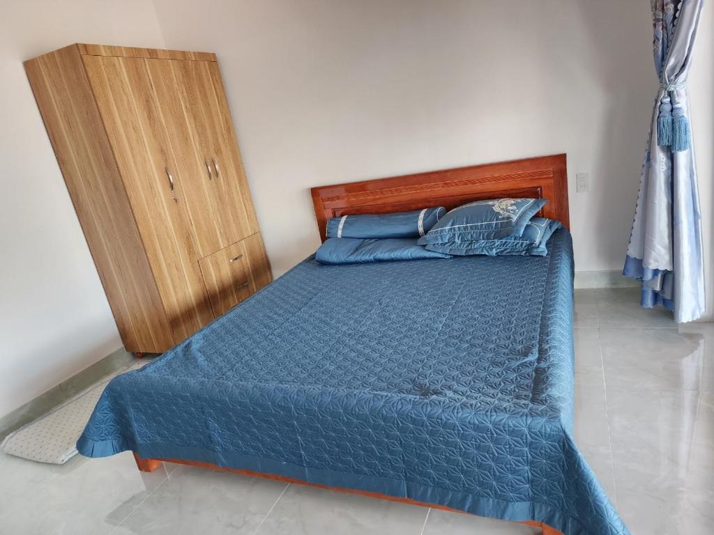 Namban的住宿－OVi farmstay Nam Ban - Lâm Hà，一间卧室配有蓝色的床和木制橱柜