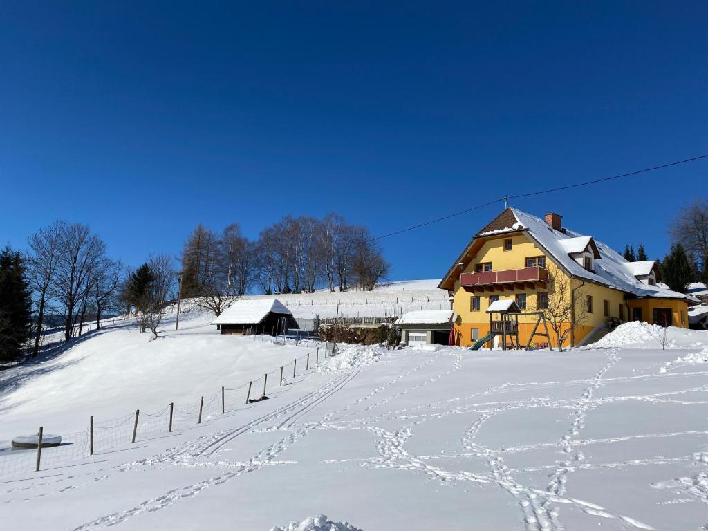 une maison sur une colline enneigée avec des empreintes de pieds dans la neige dans l'établissement Biohof Kroisleitner, à Sankt Jakob im Walde