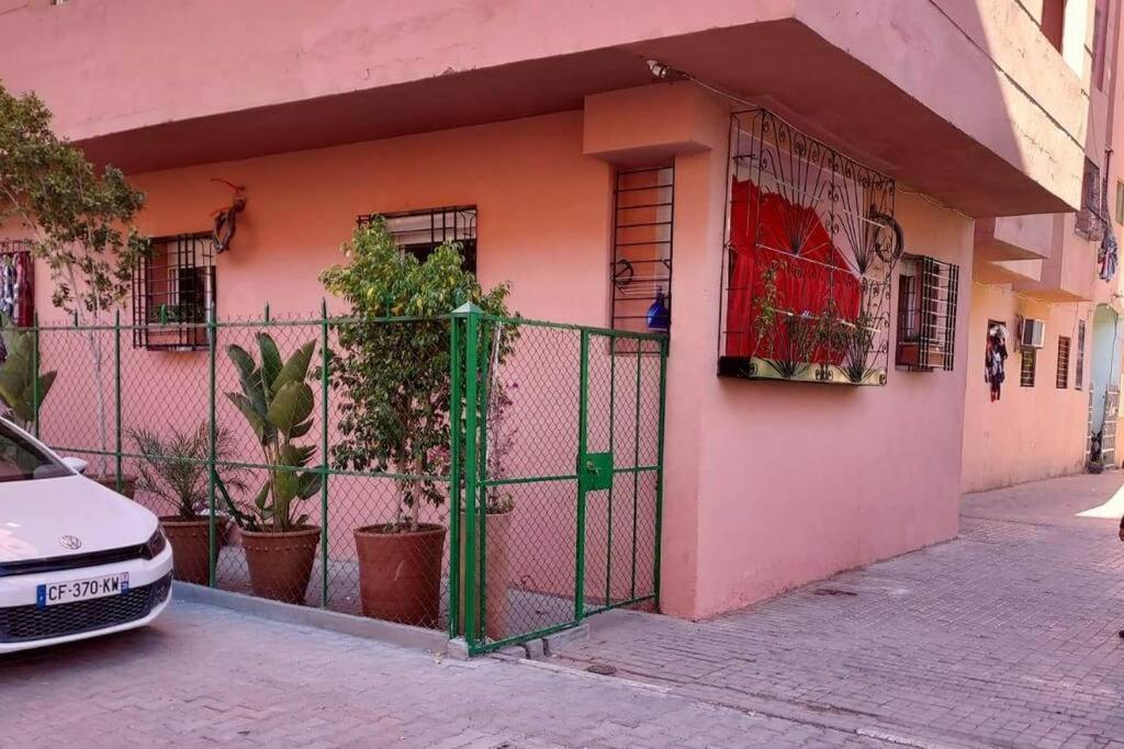una casa rosa con una puerta verde delante de ella en Pied à terre proche aéroport, en Marrakech