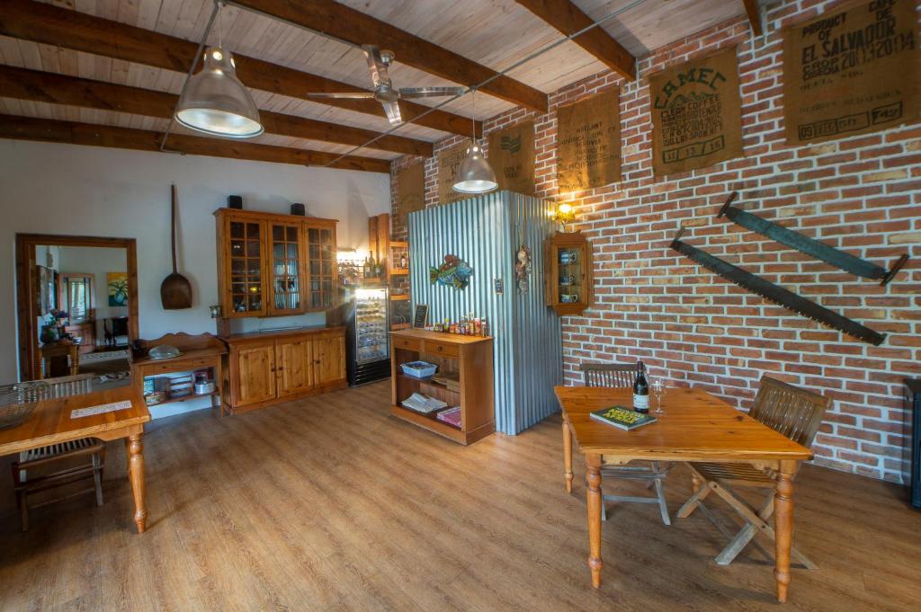 un soggiorno con tavoli in legno e un muro di mattoni di At the Woods Guest House a Stormsrivier
