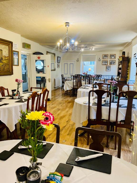 un comedor con mesas y sillas en un restaurante en Newcastle Arms Hotel en Coldstream