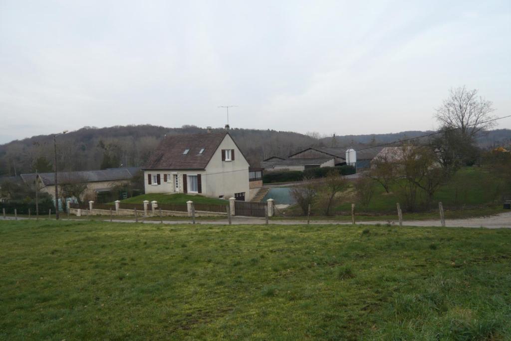Ein weißes Haus auf einem Feld neben einem Feld in der Unterkunft Gite de la Vallée de Mai 