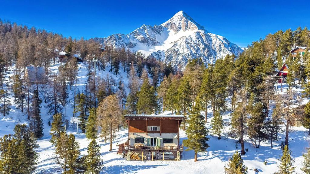 a house in the snow in front of a mountain at Chalet Monti Della Luna 7, Emma Villas in Bousson