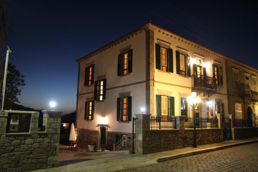 ein großes weißes Gebäude in der Nacht mit eingeschaltetem Licht in der Unterkunft Artemis Traditional Hotel in Mirina