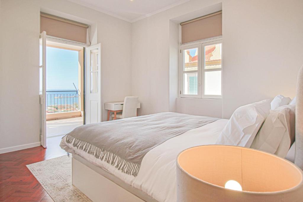een witte slaapkamer met een bed en uitzicht op de oceaan bij Pi Houses in Funchal