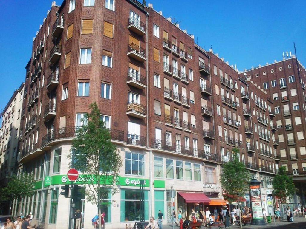 un grande edificio in mattoni su una strada di città con persone di fronte di Paprika Apartment Studio a Budapest
