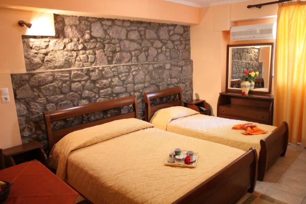 a bedroom with two beds and a stone wall at Artemis Traditional Hotel in Myrina