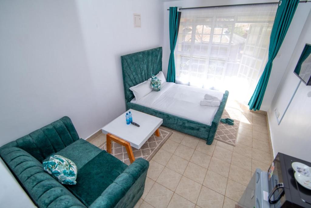 uma sala de estar com um sofá e uma cama em The Green Apartment em Ruaka