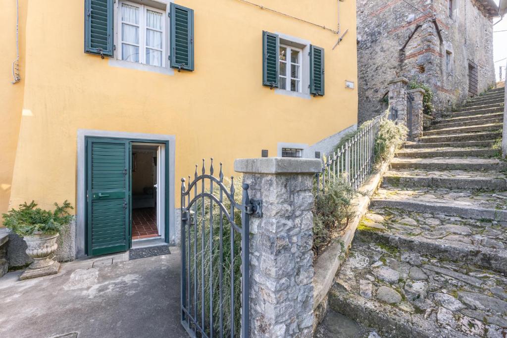 un bâtiment jaune avec des volets verts et un portail dans l'établissement Grillo Rosso Taverna, à Molazzana