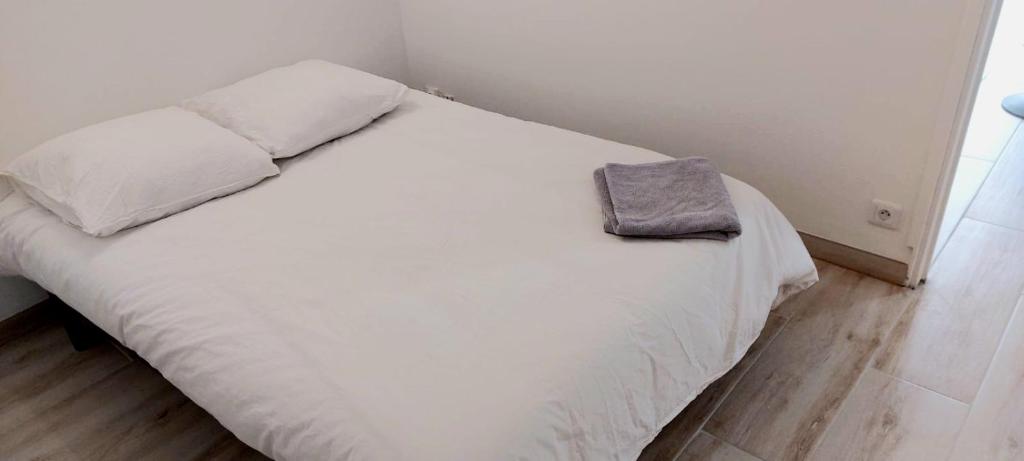 ein weißes Bett mit einer Handtasche darüber in der Unterkunft Le marbré de Vendargues in Vendargues