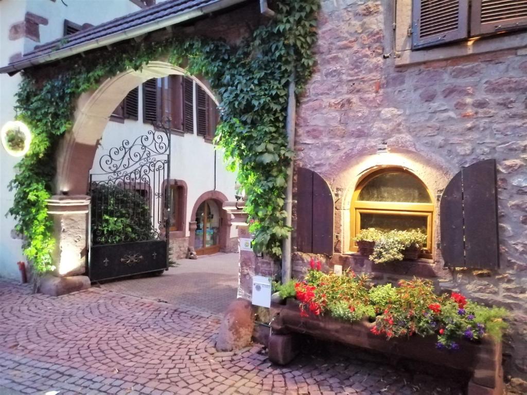 un edificio in pietra con dei fiori di fronte di GÎTE DE LA FONTAINE a Wangen