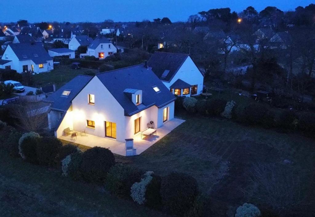 une maison blanche avec des lumières allumées dans une cour la nuit dans l'établissement Maison TY LAOUEN, à Locoal-Mendon