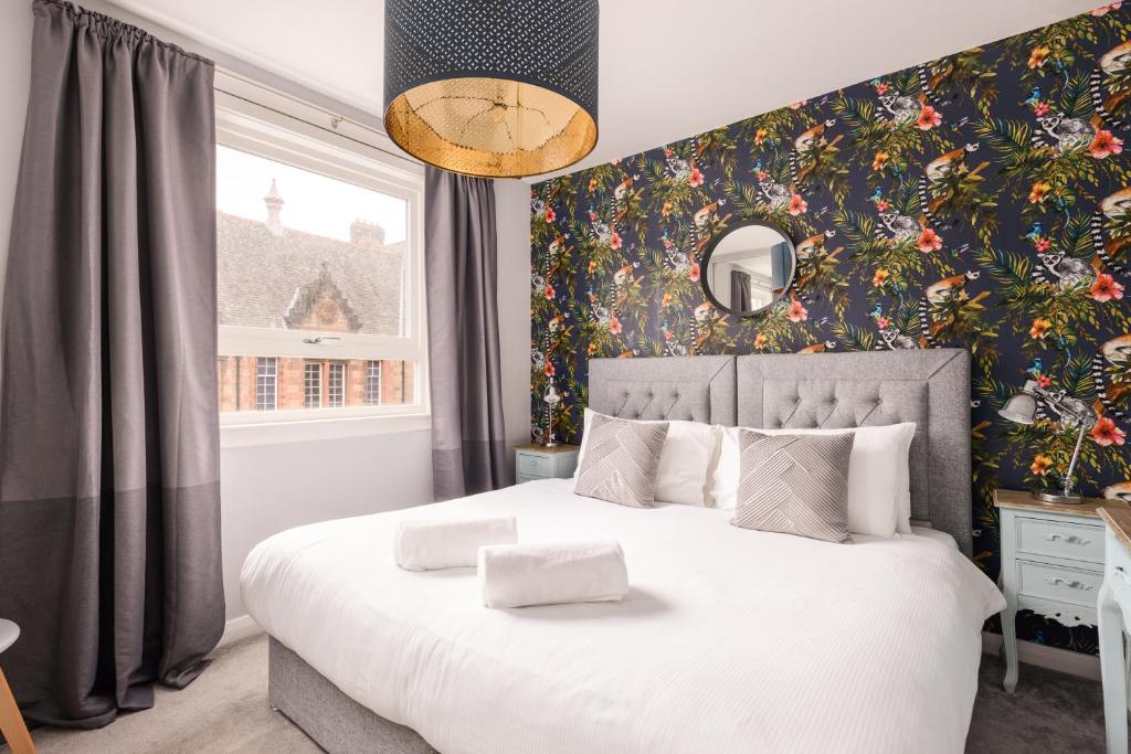 愛丁堡的住宿－The Canongate Apartment，一间卧室配有一张带花卉壁纸的大床