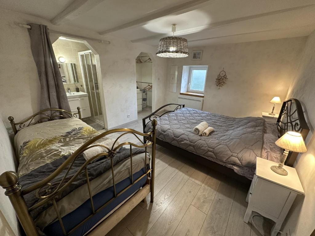 a bedroom with two beds and a lamp on a table at La Ferme aux Diligences in Neydens