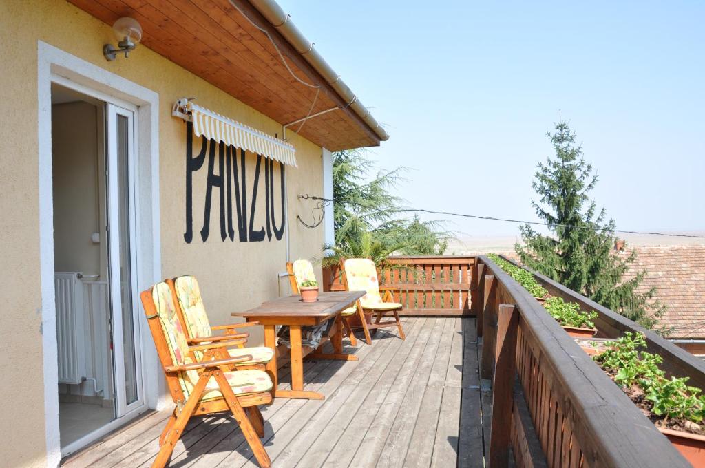 Gloriett Panzió في Fertőboz: سطح خشبي مع كراسي وطاولة خشبية