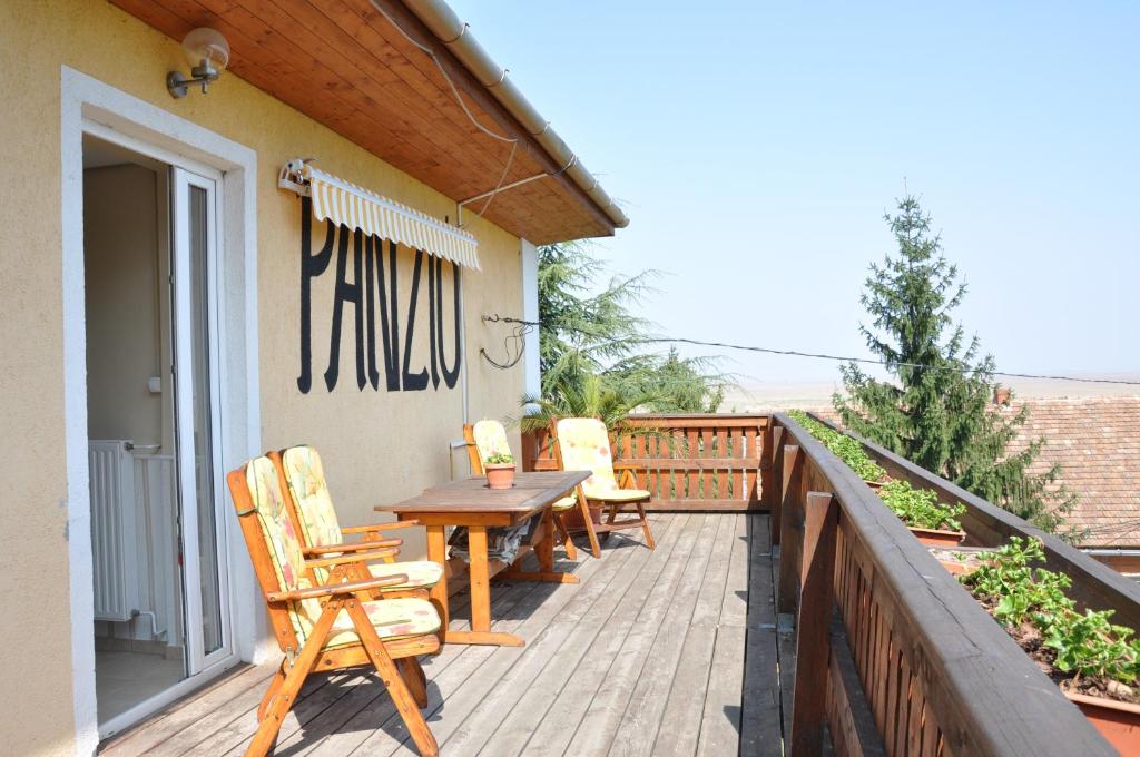 una terraza de madera con sillas y una mesa de madera. en Gloriett Panzió en Fertőboz