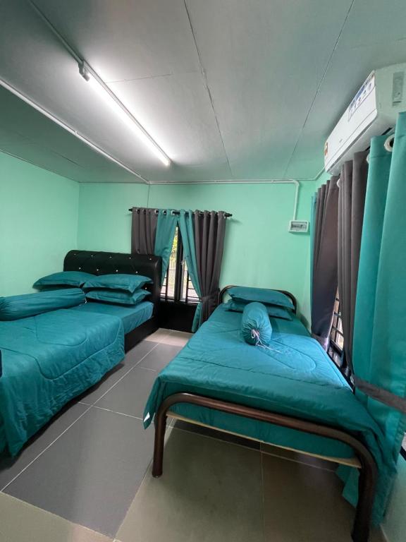 2 Betten in einem Zimmer mit blauen Wänden in der Unterkunft Mini Homestay Arifz Zai in Batu Kurau