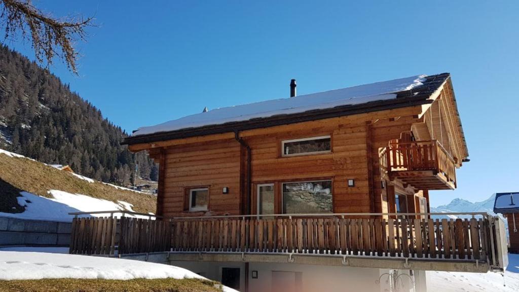 une cabane en rondins dans la neige avec un balcon dans l'établissement Chalet Matterhornsicht, à Naters