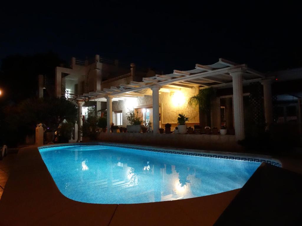 a swimming pool in front of a house at night at Hostal Residencial La Paloma in Calpe