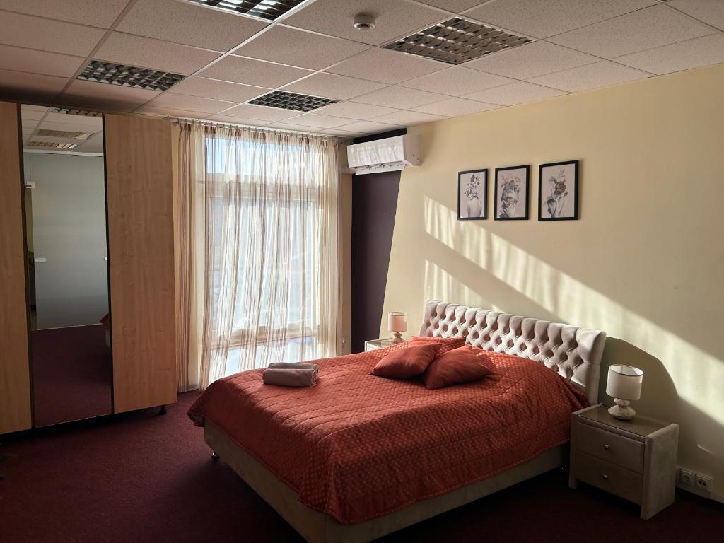 a bedroom with a bed with red sheets and a window at Draugystės apartmentai in Kaunas